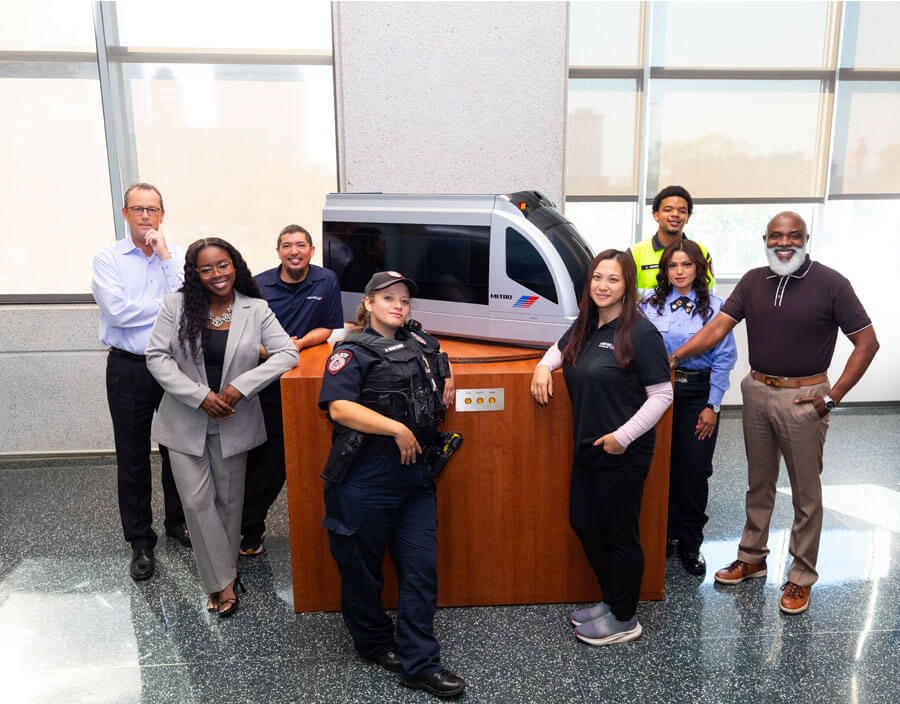 METRO employees standing around a tabletop replica of a METRORail train.